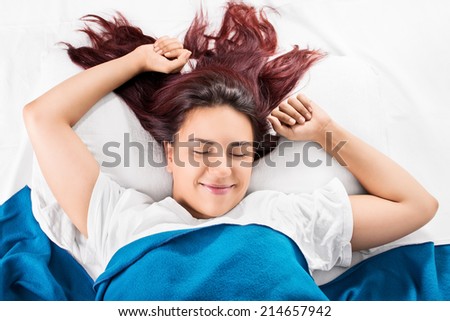 Young girl waking up while stretching in bed in the morning