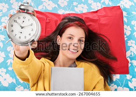 Done my read right on time. Young girl holding a book and alarm clock
