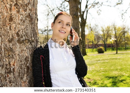 I\'m very glad i heard you. Young girl in park talking on the phone with a dear person.