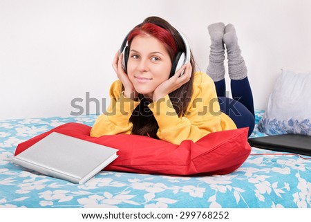 Music pause after study. Young girl in her bed relaxing with music after studying.