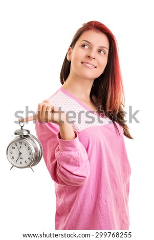 Wake up, its a beautiful day. Smiling young girl in pyjamas holding an alarm clock, isolated on white background