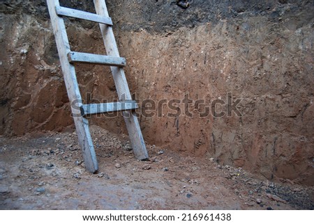 Old wooden ladder in the pit