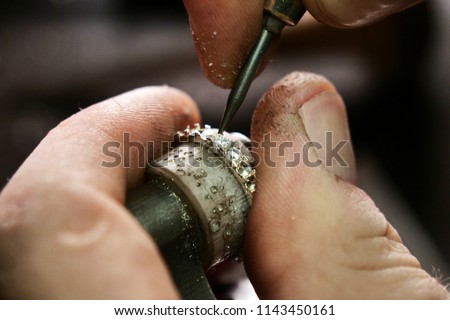 Close up of a goldsmith\'s hand making a gold or silver ring or a diamond using goldsmith\'s tools. For this work it takes precision and patience. Concept of: tradition, luxury, jewelry.