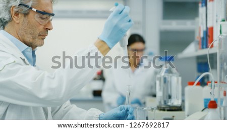 Portrait of male scientist with a pipette analyzes a liquid to extract the DNA and molecules in the test tubes in laboratory. Concept: research,biochemistry, pharmaceutical medicine