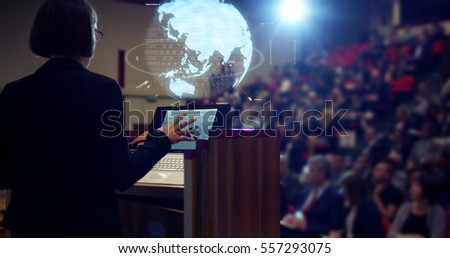A woman holds a speech to the audience in an auditorium on a convention of economics and finance their business.concept: world economy, futuristic conference, holograms,future business world
