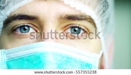 close up portrait of a surgeon or doctor with mask and headset ready for operation in hospital or clinic. The surgeon smiles safe and proud of himself. Concept of medicine, hospitals and doctors, care
