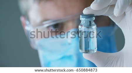 Portrait of a doctor or surgeon in a medical mask, respirator, brown eyes, goggles, holds tests in a hospital or clinic. Concept: first medecine help, help treat people, surgery, doctors, laboratory