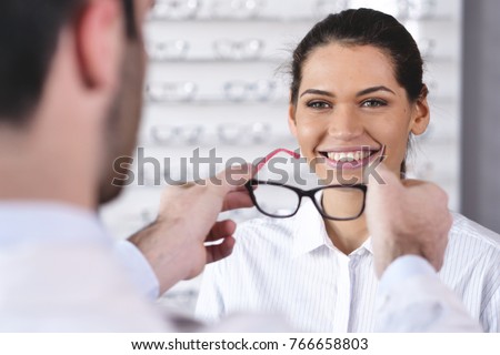 an ophthalmologist doing a visual examination for a customer at an optical center. Try the spectacles to the patient. Concept of: medical examination, assistance, optics and customer care.