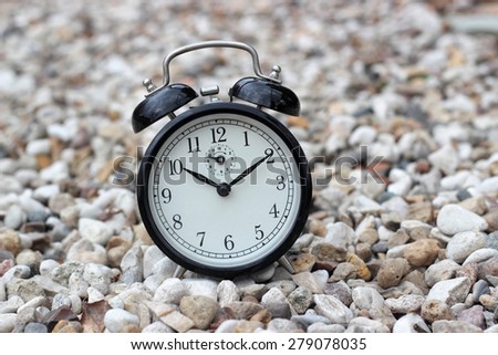 Vintage alarm clock on stones background closeup.