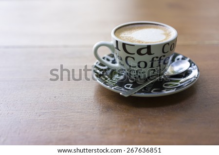 leaf shape latte art coffee in the graphic ceramic white cup on wooden background