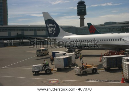 Loading up a plane at Vancouver Airport. Workers are placing baggage and food on the plane