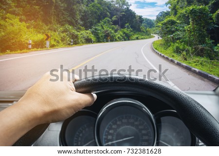 View on the dashboard of the truck driving.The driver is holding the steering wheel. Forest road is in front of the car.