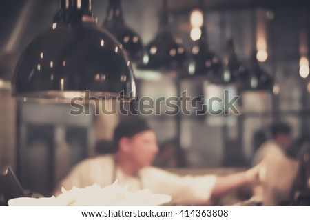Blurred Restaurant Chef: Chef cooking in the open kitchen, customer can see cooking at food counter