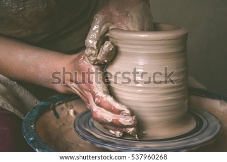Creating a jar or vase of white clay close-up. Master crock. Man hands making clay jug macro. The sculptor in the workshop makes a jug out of earthenware closeup. Twisted potter\'s wheel.