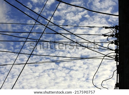 Silhouettes pole and wires against the blue sky with cloud