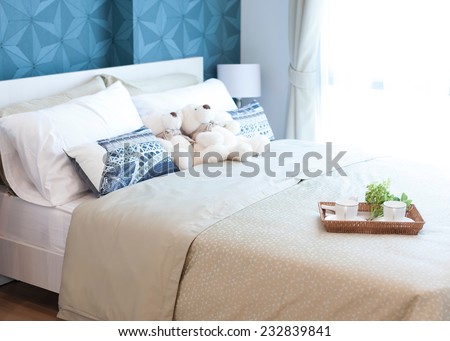 Decorative tray with teddy bear, tea set and flower on the bed