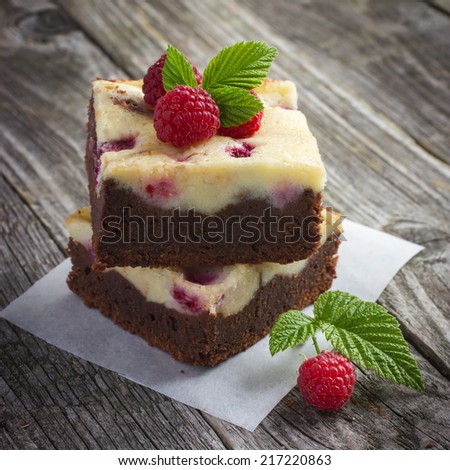 raspberry cheesecake brownies on a rustic wooden background, square image