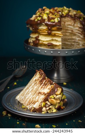 piece of crepe cake with custard cream and chocolate topping and nuts