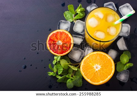 Fresh orange juice,  mint and ice on dark background, top view, copy space