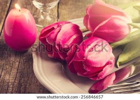 Spring table setting with three pink tulips and candle egg for Easter, toned