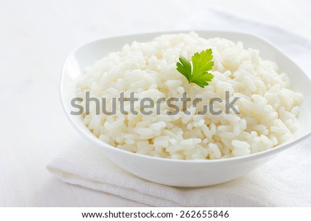 White rice in bowl on white background, selective focus