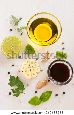 Ingredients for salad dressing. Olive oil, balsamic vinegar, garlic, lemon, herbs and spices on white background, top view