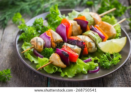 Grilled chicken and vegetable kebabs on wooden background