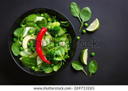 Healthy food. Fresh green salad on black background, top view