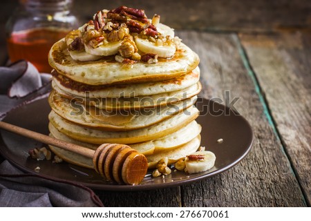 pancakes with banana, nuts and honey on wooden background