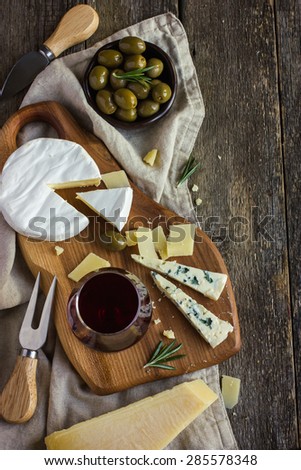 Assortment of various types of cheese on wooden board, top view