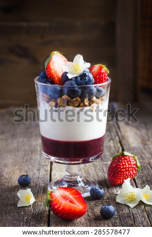 dessert with fresh berries,  cream cheese, granola and berries  jam, on rustic background
