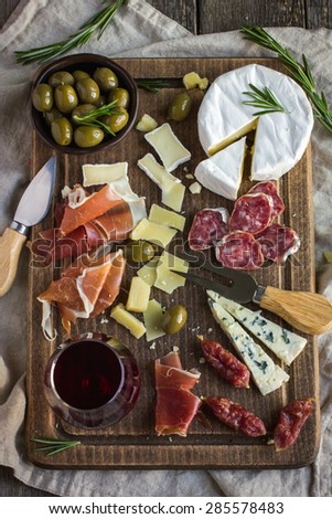 Assortment of various types of cheese and meat on wooden board, top view