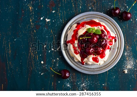 meringues pavlova cake with fresh cherry on dark blue background, top view, copy space