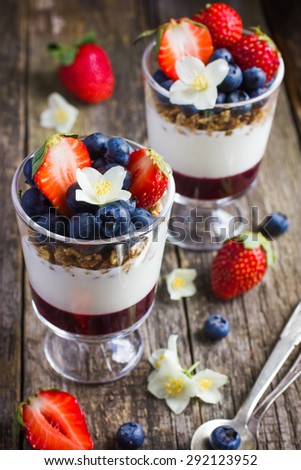 dessert with fresh berries,  cream cheese, granola and berries  jam, on rustic background