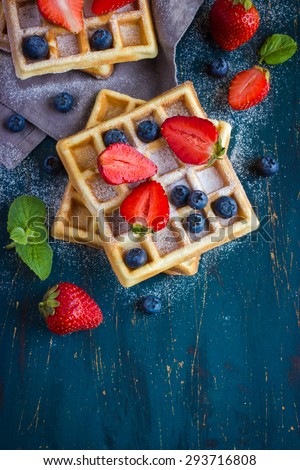 belgian waffles with fresh berries on dark blue background, top view