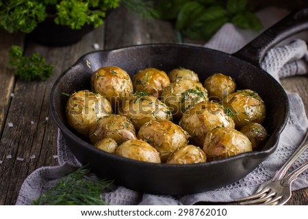 Oven Baked potatoes with herbs on cast iron pan, selective focus