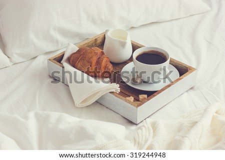 breakfast in bed,  tray with cup of coffee and  croissant, toned