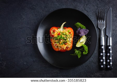 pepper staffed with couscous and vegetables on black plate, top view, copy space