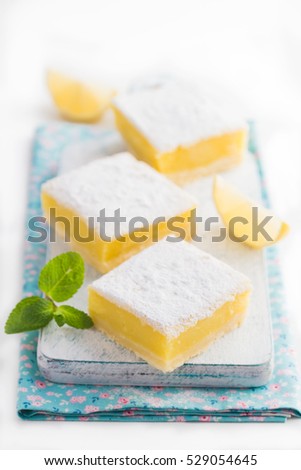 freshly baked lemon bars (or lemon  squares) with powdered sugar on white ba?kground, selective focus