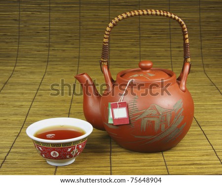 Pouring Chinese tea with an authentic Chinese teapot and cup on a bamboo background