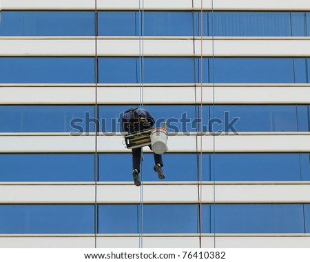 View of some daredevil window washers whom specialize washing windows by hand of very tall building. They are called Cliffhangers