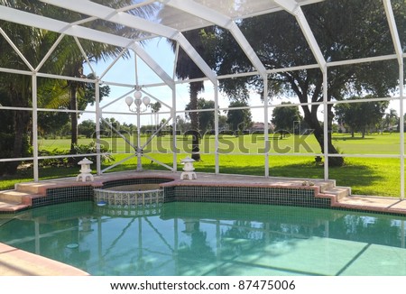 Beautiful residential screened-in swimming pool with patio and patio furniture.