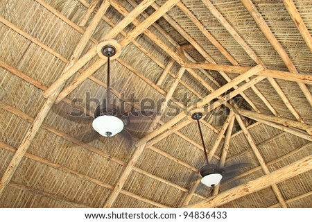 Ceiling rafters of a hand build tiki hut with ceiling fans