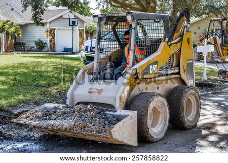 Miami, Florida - November 07, 2014:  A front loader working on a construction site in a residential neighborhood, improving the draining system for the wet rainy season