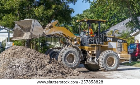 Miami, Florida - November 07, 2014:  A front loader working on a construction site in a residential neighborhood, improving the draining system for the wet rainy season