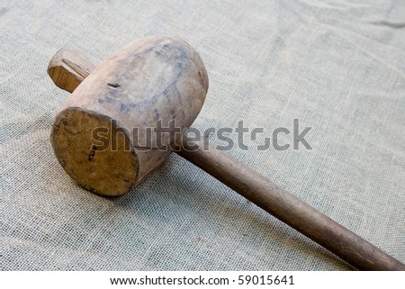 Old wooden mallet hammer on burlap background