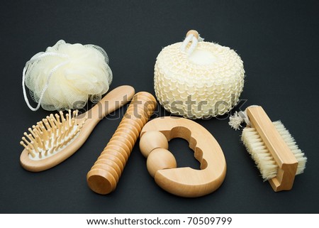 Bath set - massage brush with wooden studs, massage roller, sponge, loofah on a dark background.