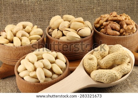 Abstract view of the mixture of nuts in a round wooden form on the background of natural fabrics