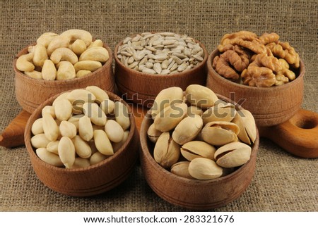 Abstract view of the mixture of nuts in a round wooden form on the background of natural fabrics