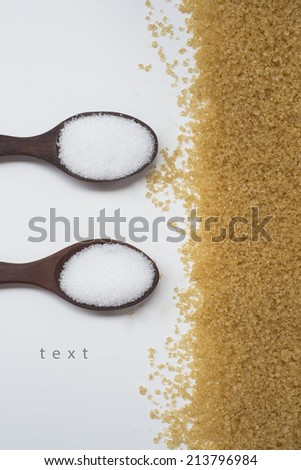 white sugar on wooden spoon with brown sugar on white background